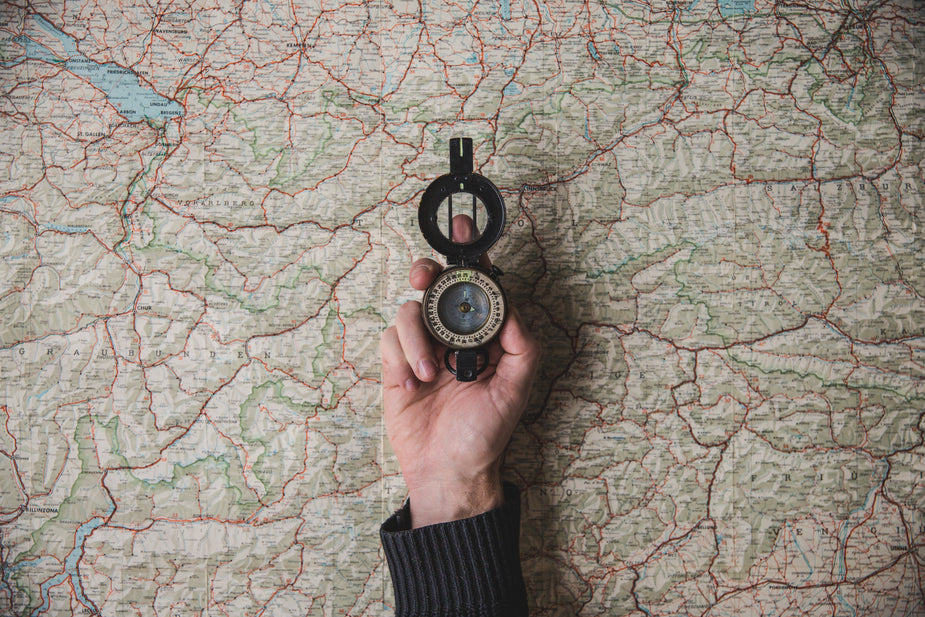 hand holding a compass over a map finding where to start