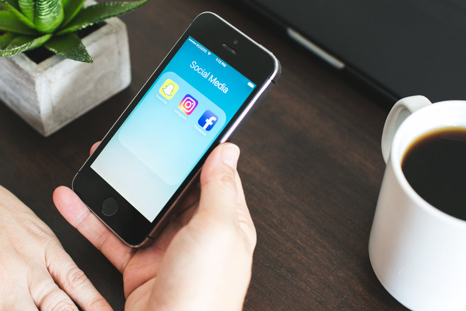 Social media icons displayed on an iPhone being viewed at home at the table.