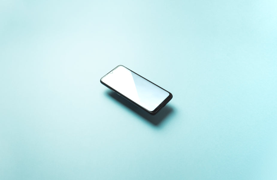 A black cellphone floats in the middle of the frame above a light blue background.