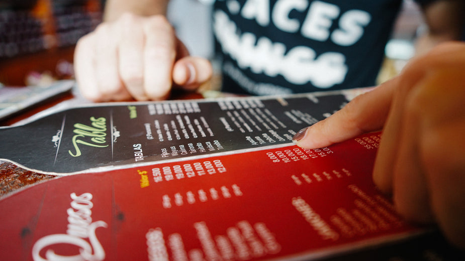 Having many choices at a restaurant, a hand passes over a menu with a lot of options.