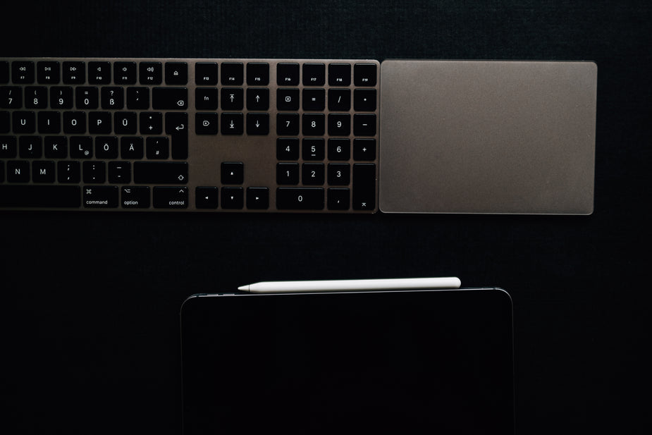 A scopists, court reporters, and transcriptionists computer keyboard equipment on a black surface with a tablet and white pencil below it.