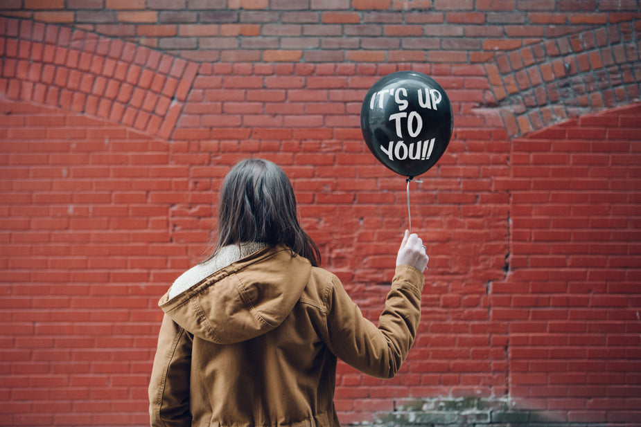 Someone stands and is clearly inspired as they hold a ballon with motivational writing on it. "Up To You" spelled out is a great mantra for you or anyone who needs to be reminded that only you can take your life to the next level. Let's do this!