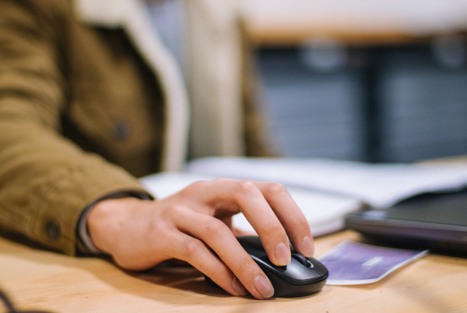 A close up of a person using a mouse to operate their computer.