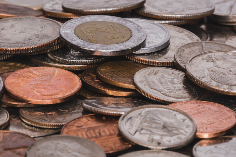 An assortment of coins is piled up and seen close up and from the side. All the colors and layers of metal are a great symbol of savings and currency from around the world.