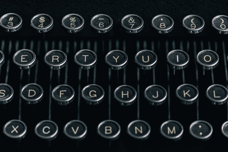 The Keys and Keytops of a classic antique typewriter. A bit dusty from time and age, the round silver and black keys shine in the light of the room, hanging above the typebars they are attached too. Ready to pound out some poetry, a letter or even a novel the old fashioned way.