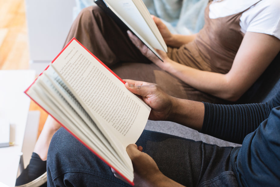 Two people sitting beside each other relax and read.