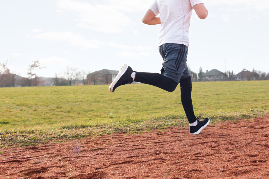 A runner takes a big step and gets his stride as he runs around an outdoor track and field track.  Metaphor for trying to increase typing speed