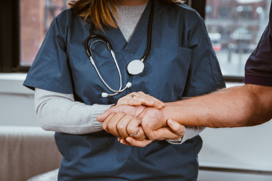 A doctor holds the hand of their patient in comfort and help. Healing can come in many forms.