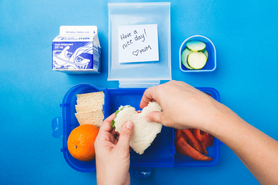 A pair of hands adds the final touch to a healthy packed lunch - a heart-shaped sandwich. staying helathy while working from home