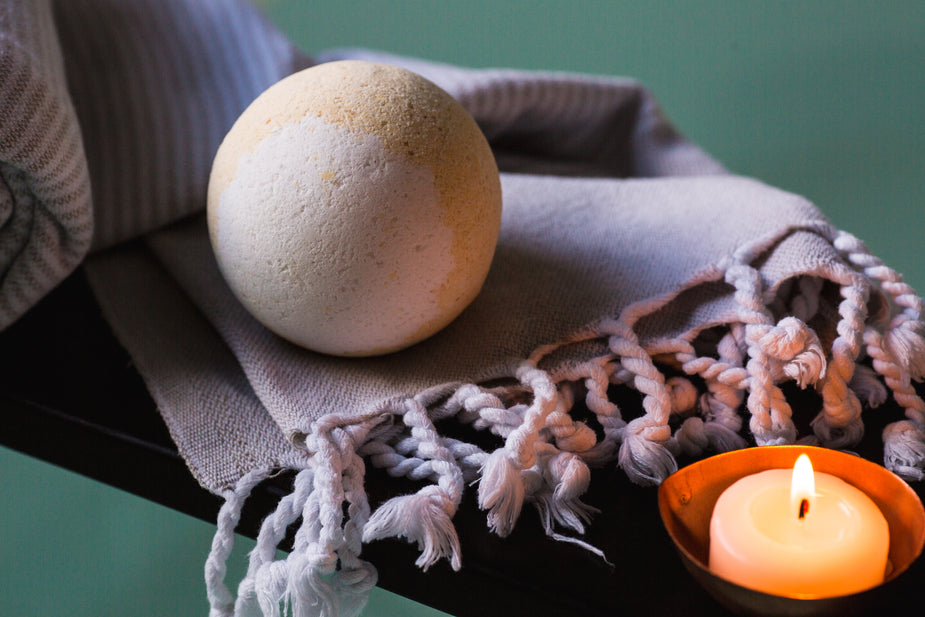 Yellow and white bath bomb on purple scarf by candle. Necessary personal touches in your workspace for productivity