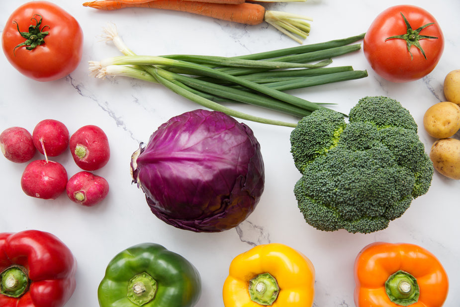 A colorful selection of fresh vegetables on a white chopping board, ready to be prepared into a delicious, healthy meal. Healthy food is essential to living healthy while working from home