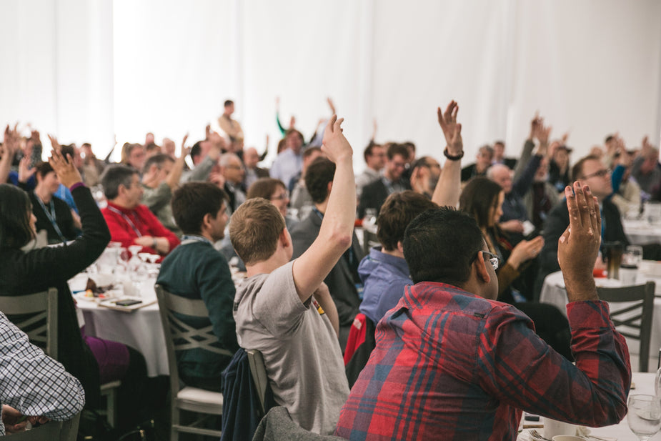 Participants raise their hands at a conference.