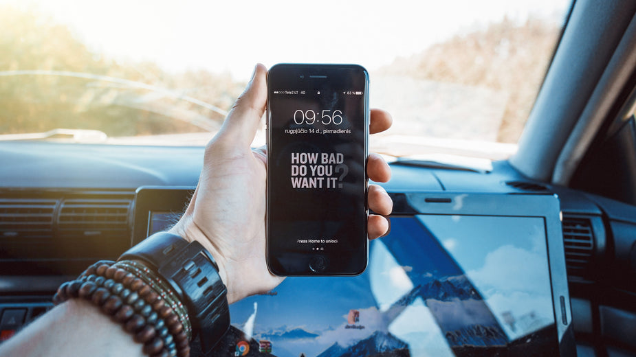 A motivational message displayed on a mobile device in the hand of a passenger in a car. On their wrist, beaded bracelets and a wristwatch. I can tell they want it bad, because they are even working while in the car!