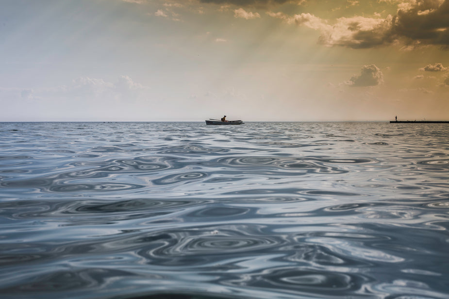 A row boat on the calm sea horizon.