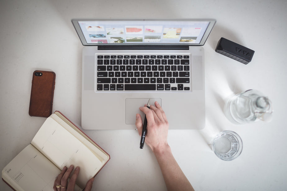 View from above of person working on laptop with planner, water, phone, speaker and pend in hand. Things you should know before becoming a scopist