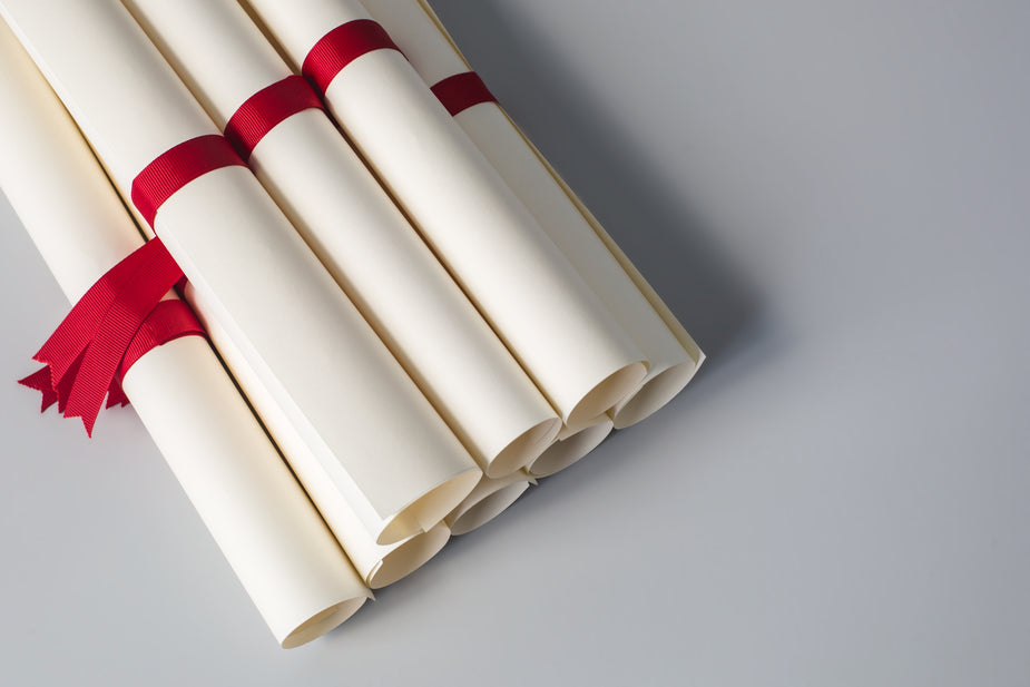 A stack of rolled up diplomas are ties with red ribbons and ready for the graduating class. useful thing to know when becoming a scopist