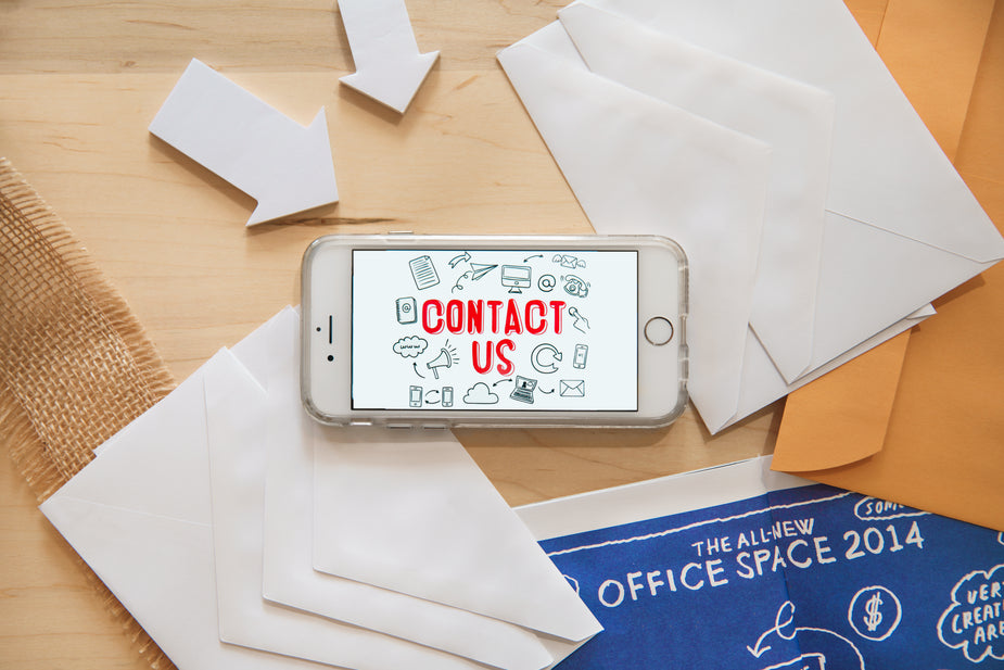 Flatlay of an iPhone with contact us on the screen, showing how easy it can be to connect and communicate on a mobile device.