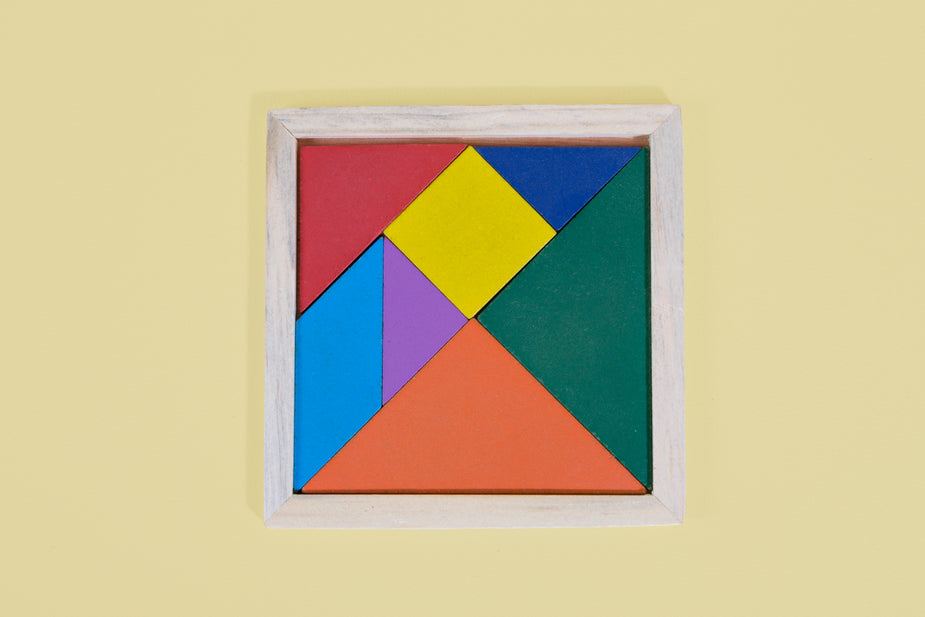 A children's puzzle in a wooden frame of colored geometric shapes.