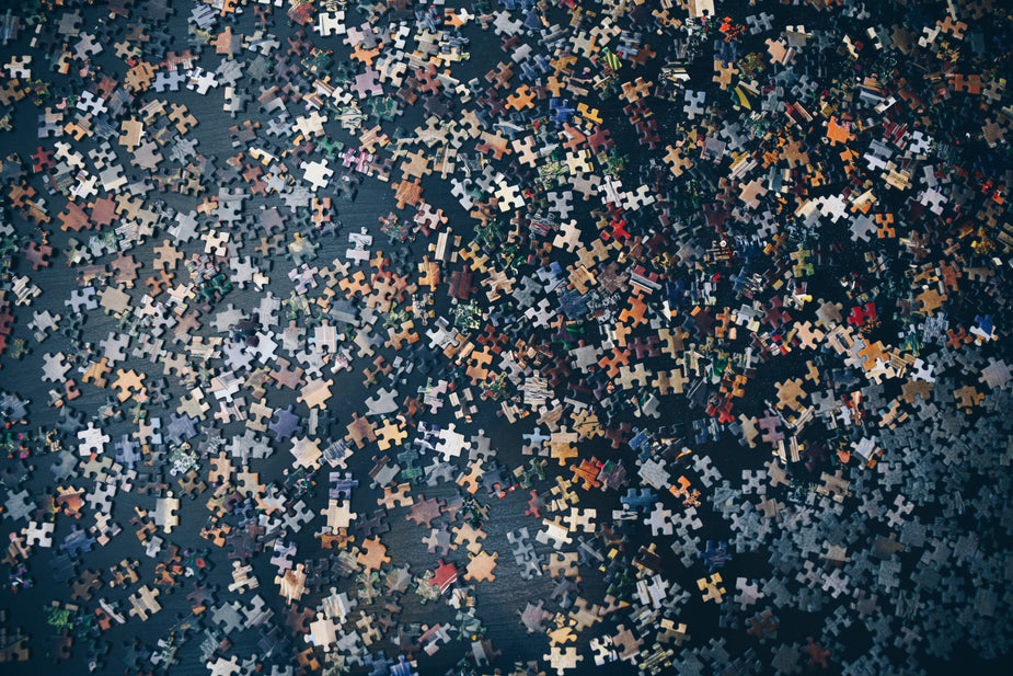 Flatlay of an overwhelming amount of unmatched puzzle pieces on a navy blue surface. A challenge! metaphor for cross talk