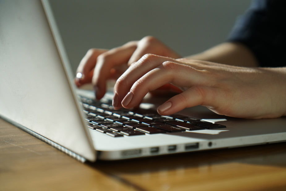 A closeup of scoofer proofreader scopist hands typing on a laptop's keyboard.