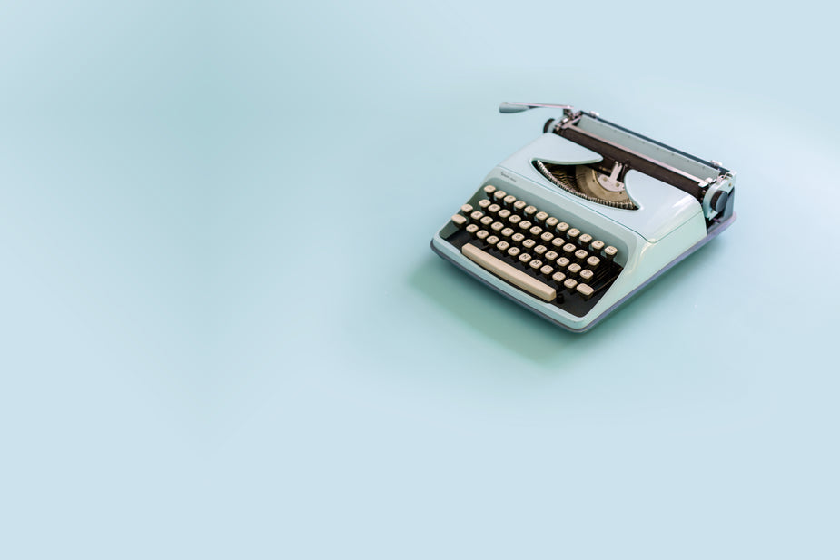 A light blue antique typewriter on a matching background. This classic keyboard once typed out letters to send the old-fashioned way.