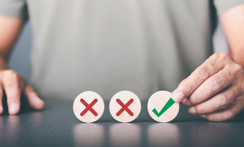 A businessman selects a wooden block with a check mark icon symbol placed on the table,The best alternative decision idea, the solution that has been analyzed and reflected