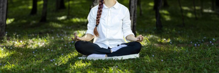 Panorama of woman relaxingly practicing meditation in the pine forest to attain happiness from inner peace wisdom for healthy mind and soul